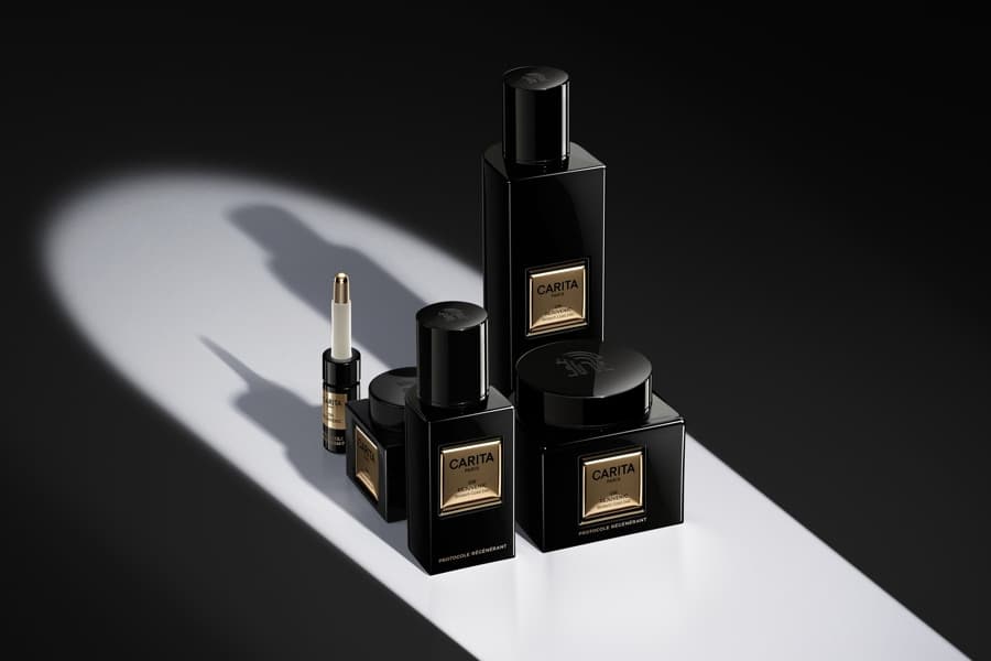 Gamme noire Carita, flacons et pots sous un rayon de lumière
